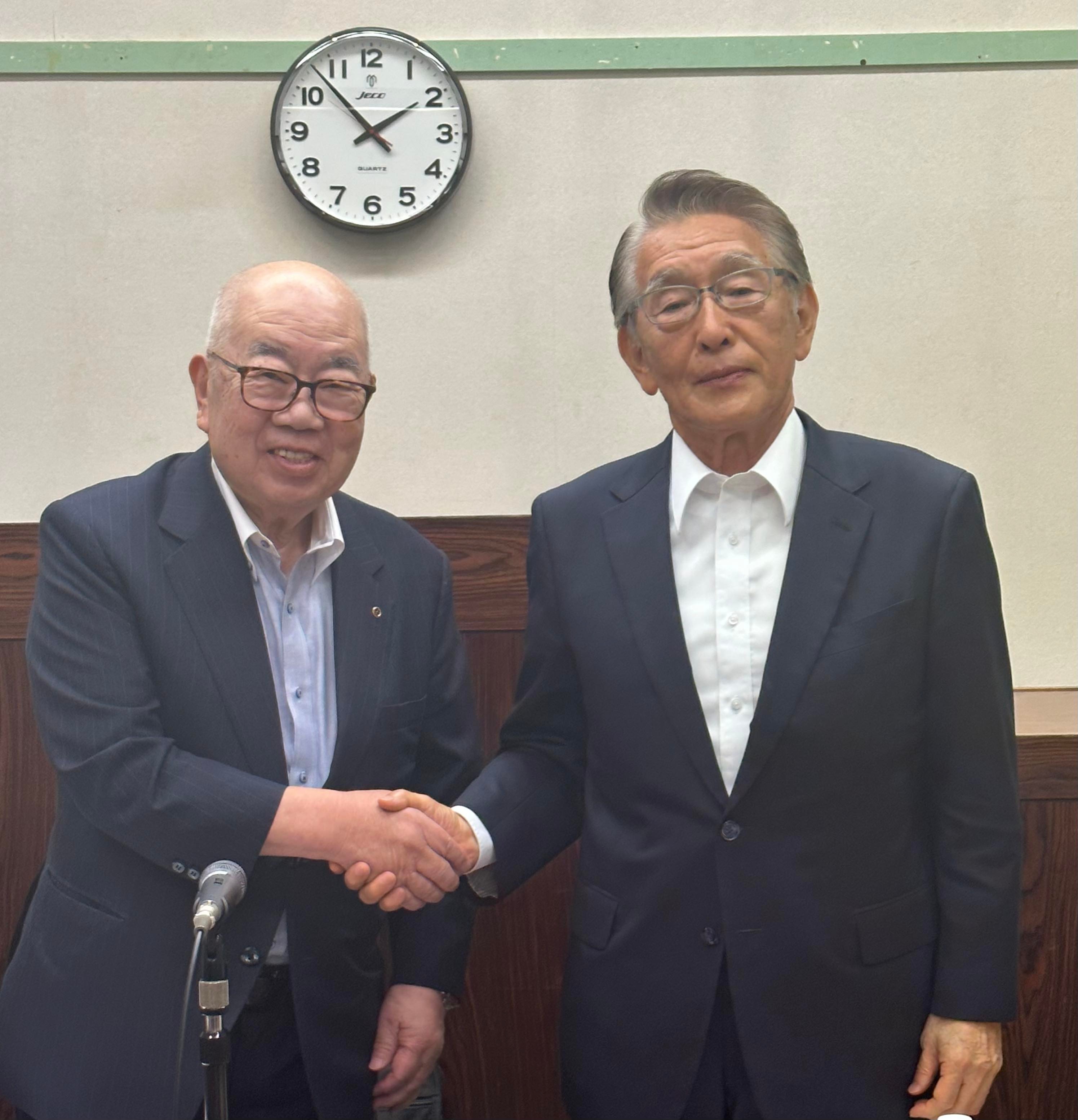 総会後に握手する桑島前会長（写真左）と山田新会長（写真右）